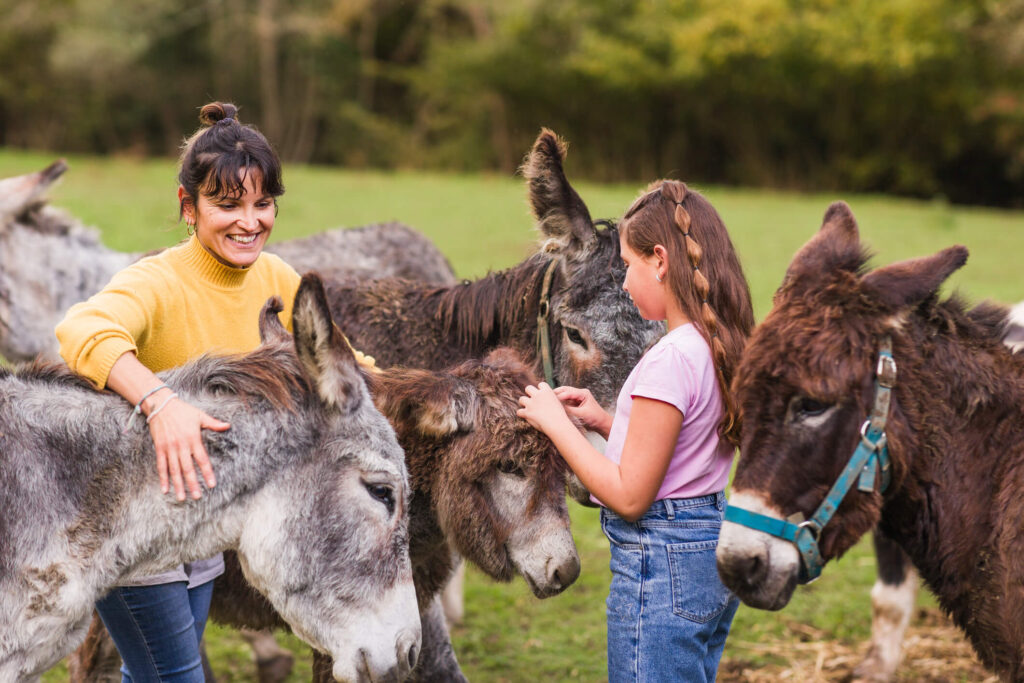 Woman and girl petting donkeys in animal sanctuary in quiros, asturias, spain